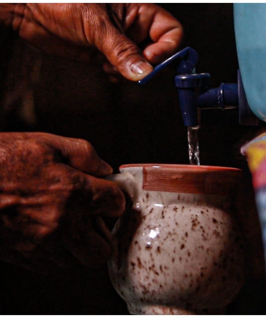 Persona llenando una vasija con agua del grifo