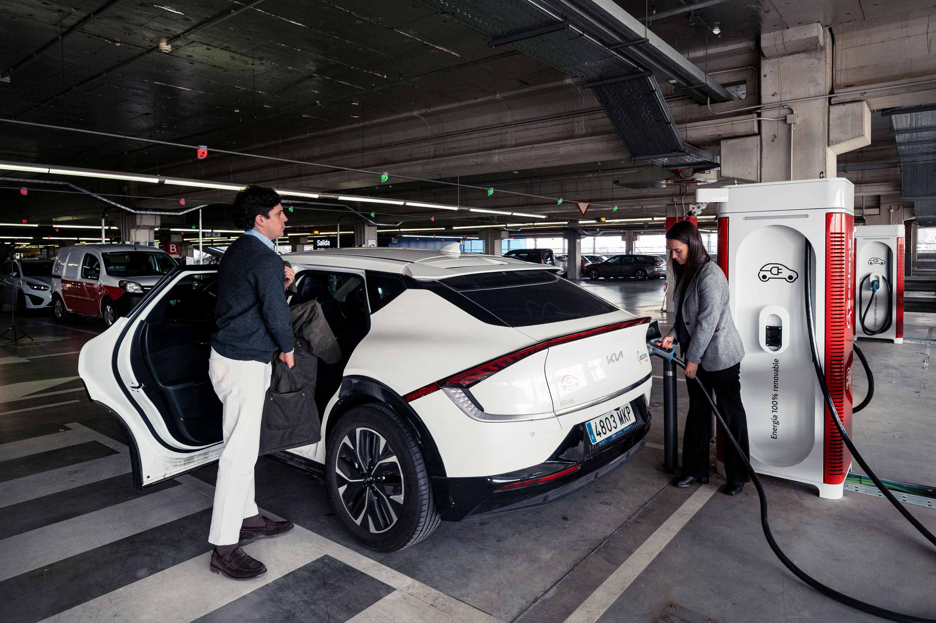 Hombre en estación de recarga cargando coche